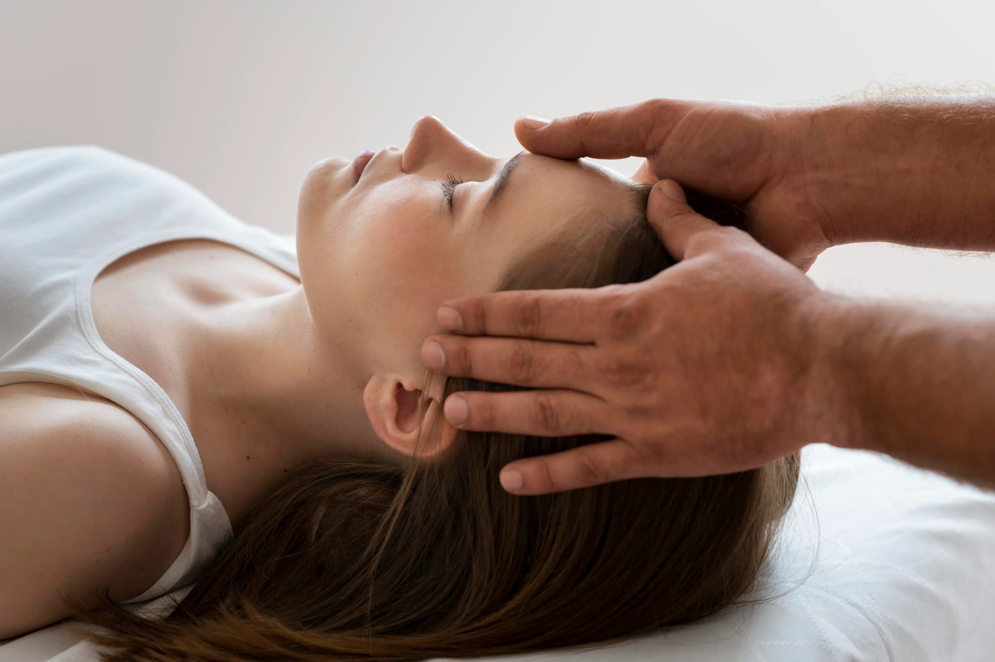 une dame alongée les yeux fermé avec les mains d'un homme posées sur son front